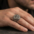 Load image into Gallery viewer, Oxidized floral signet ring worn on a finger, close-up lifestyle photo highlighting the rosette emblem and textured band

