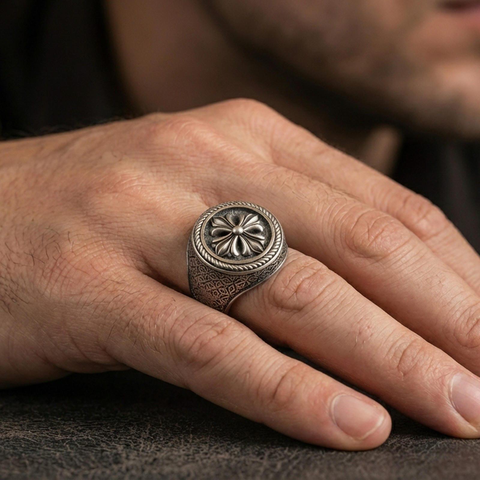 Oxidized floral signet ring worn on a finger, close-up lifestyle photo highlighting the rosette emblem and textured band