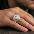 Load image into Gallery viewer, Polished silver rosette signet ring on the finger, wearable close-up emphasizing the raised flower and rope-edge frame
