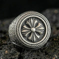 Load image into Gallery viewer, Oxidized sterling silver floral signet ring with raised six-petal rosette and rope border, macro shot on black volcanic rock
