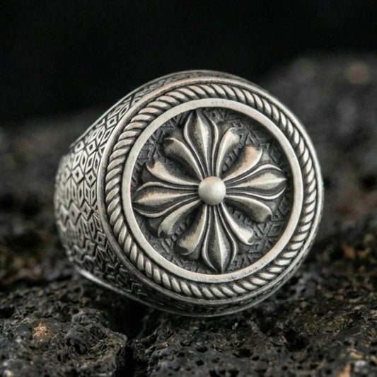 Oxidized sterling silver floral signet ring with raised six-petal rosette and rope border, macro shot on black volcanic rock