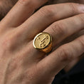 Load image into Gallery viewer, Gold plated occult sigil ring worn on a finger, lifestyle close-up showing the bold signet shape and engraved emblem
