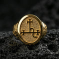 Load image into Gallery viewer, Gold plated oval signet ring with engraved sigil symbol and matte-textured face, macro photo on black volcanic rock
