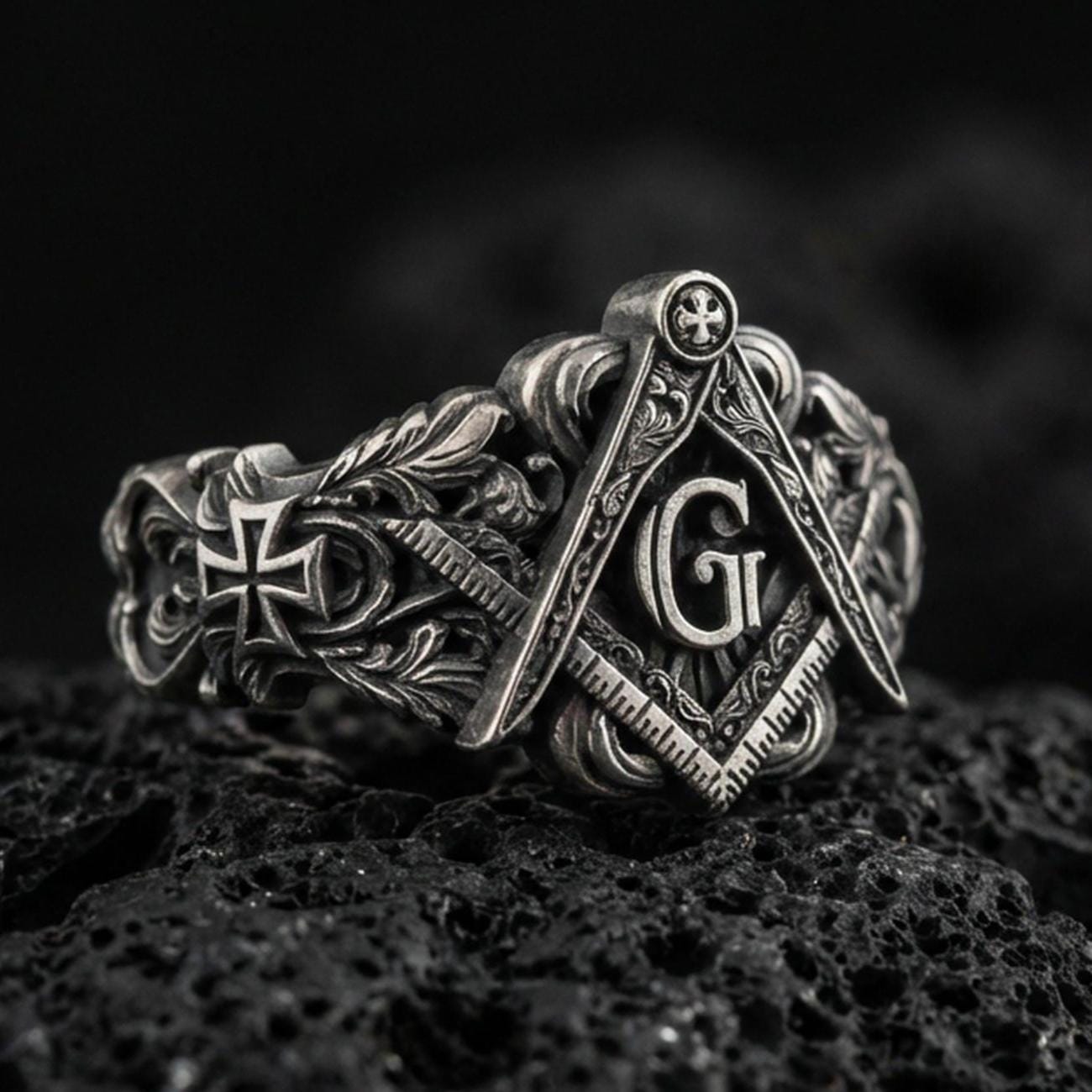 Oxidized sterling silver Masonic signet ring with square and compass emblem, “G” letter and ornate scrollwork, on black volcanic rock
