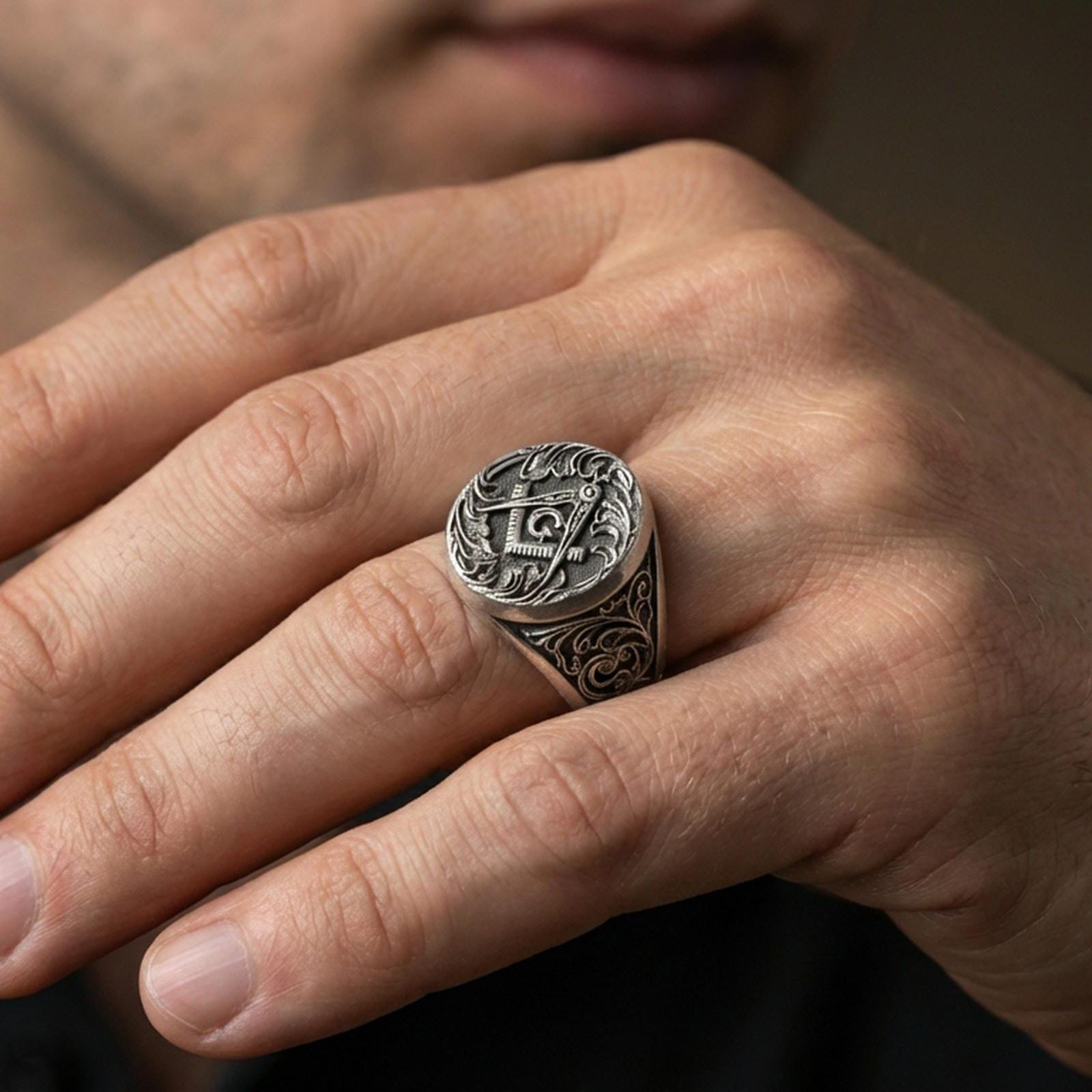Oxidized Masonic signet ring worn on a finger, close-up lifestyle photo highlighting the square and compass “G” emblem
