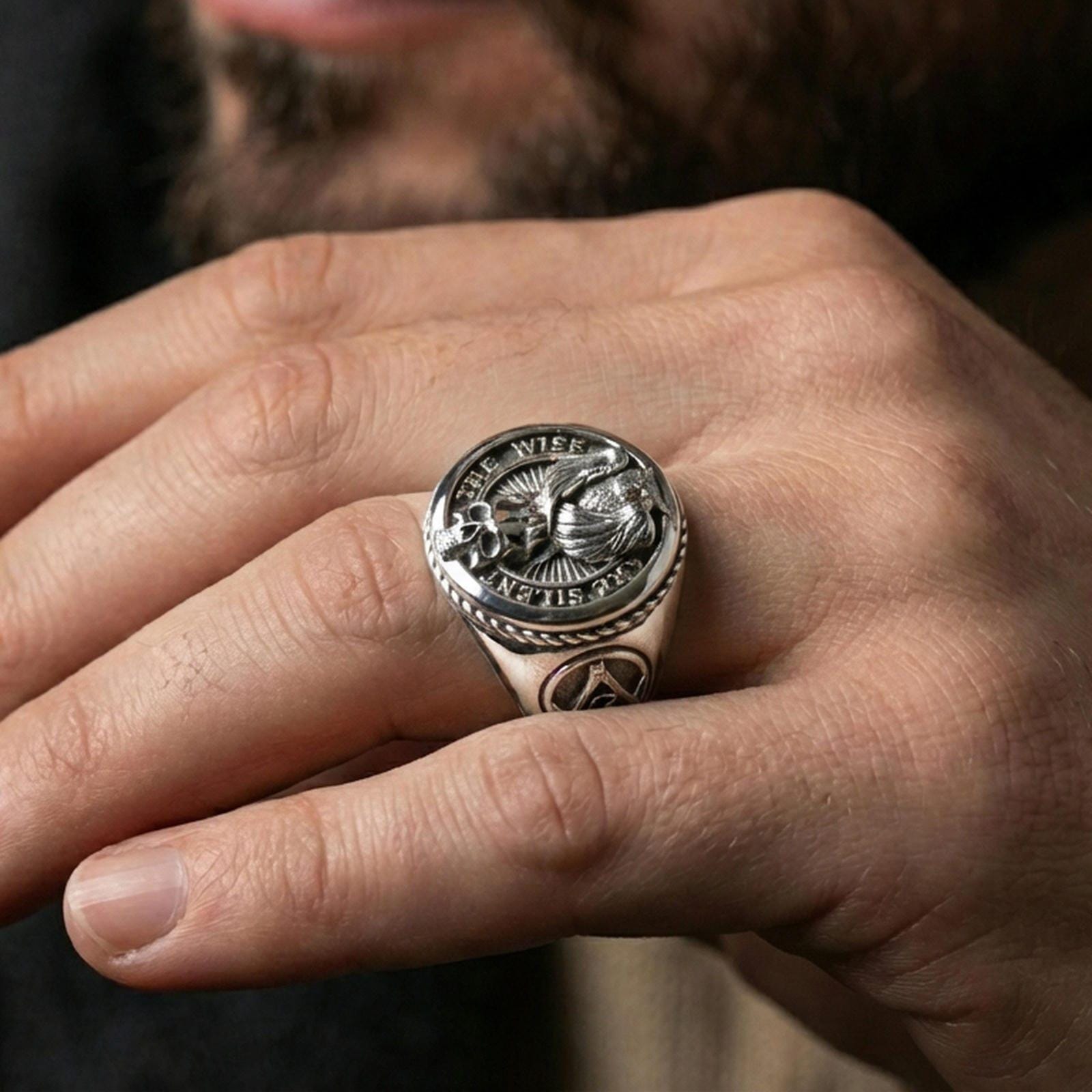 Polished silver owl signet ring on the finger, wearable macro highlighting the owl wings and skull detail