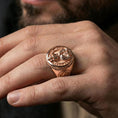 Load image into Gallery viewer, Rose gold plated owl skull signet ring on the finger, macro lifestyle photo emphasizing the braided rim and inscription

