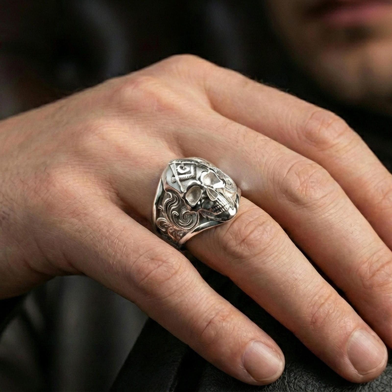 Polished silver Freemason skull ring on the finger, wearable macro showing the engraved scrollwork on the sides