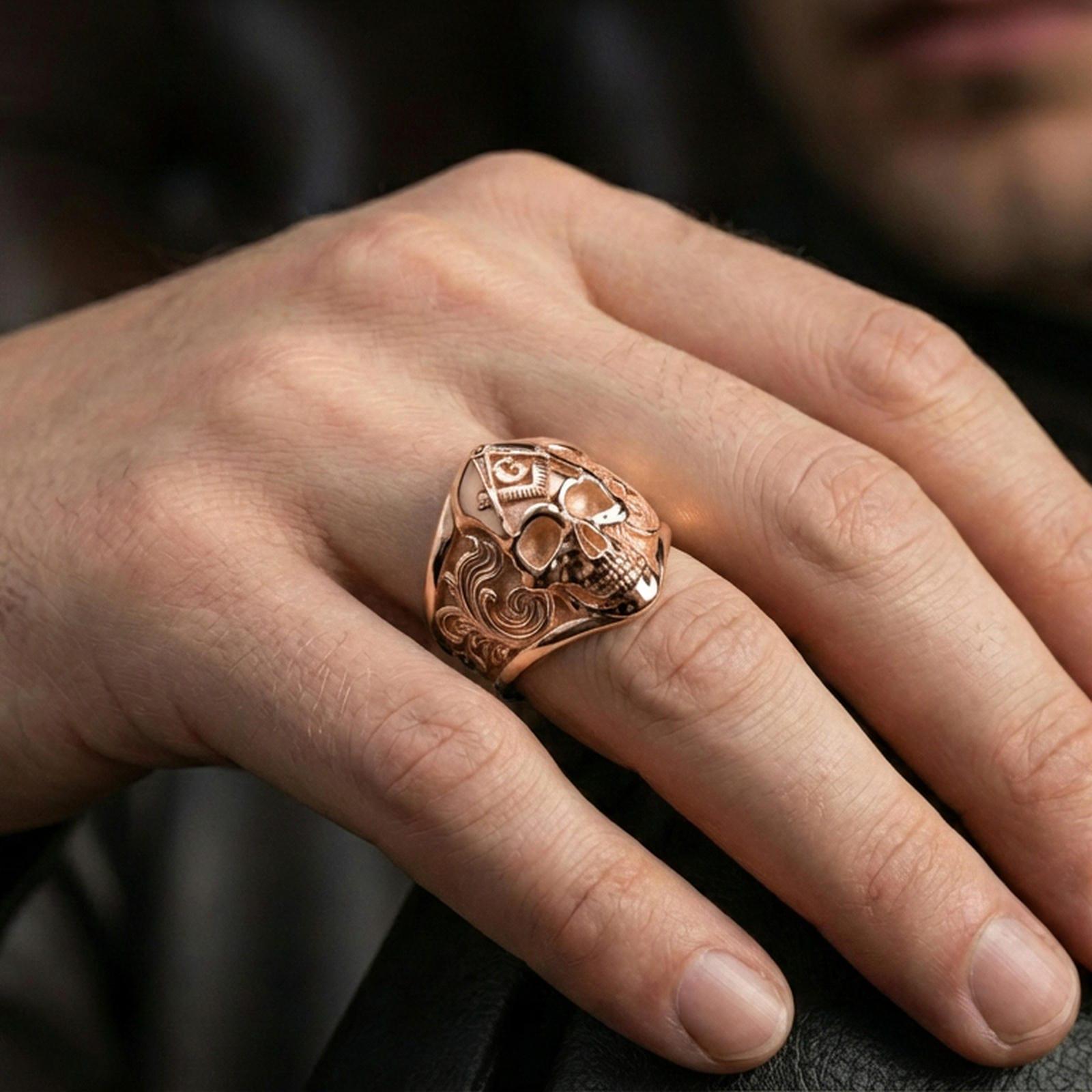Rose gold plated Freemason skull ring on the finger, macro lifestyle photo emphasizing the ornate engraving and raised emblem