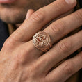 Load image into Gallery viewer, Rose gold plated eye-in-triangle ring on the finger, macro lifestyle photo showing ornate scroll engraving along the band
