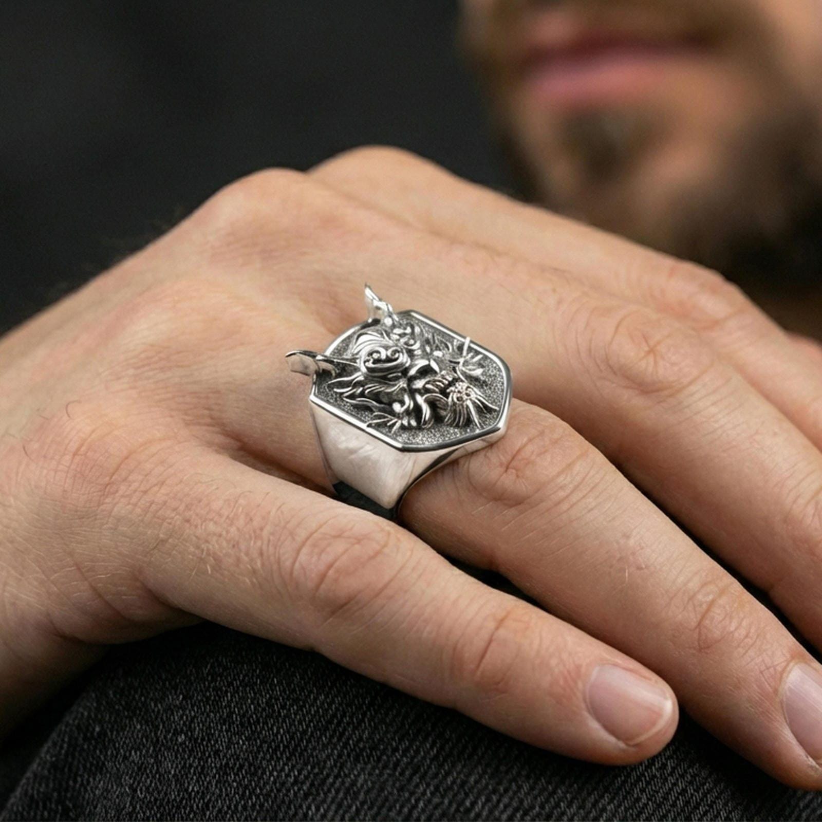 Polished silver Japanese oni signet ring on the finger, wearable macro showing the horns, eyes, and swirl engraving details
