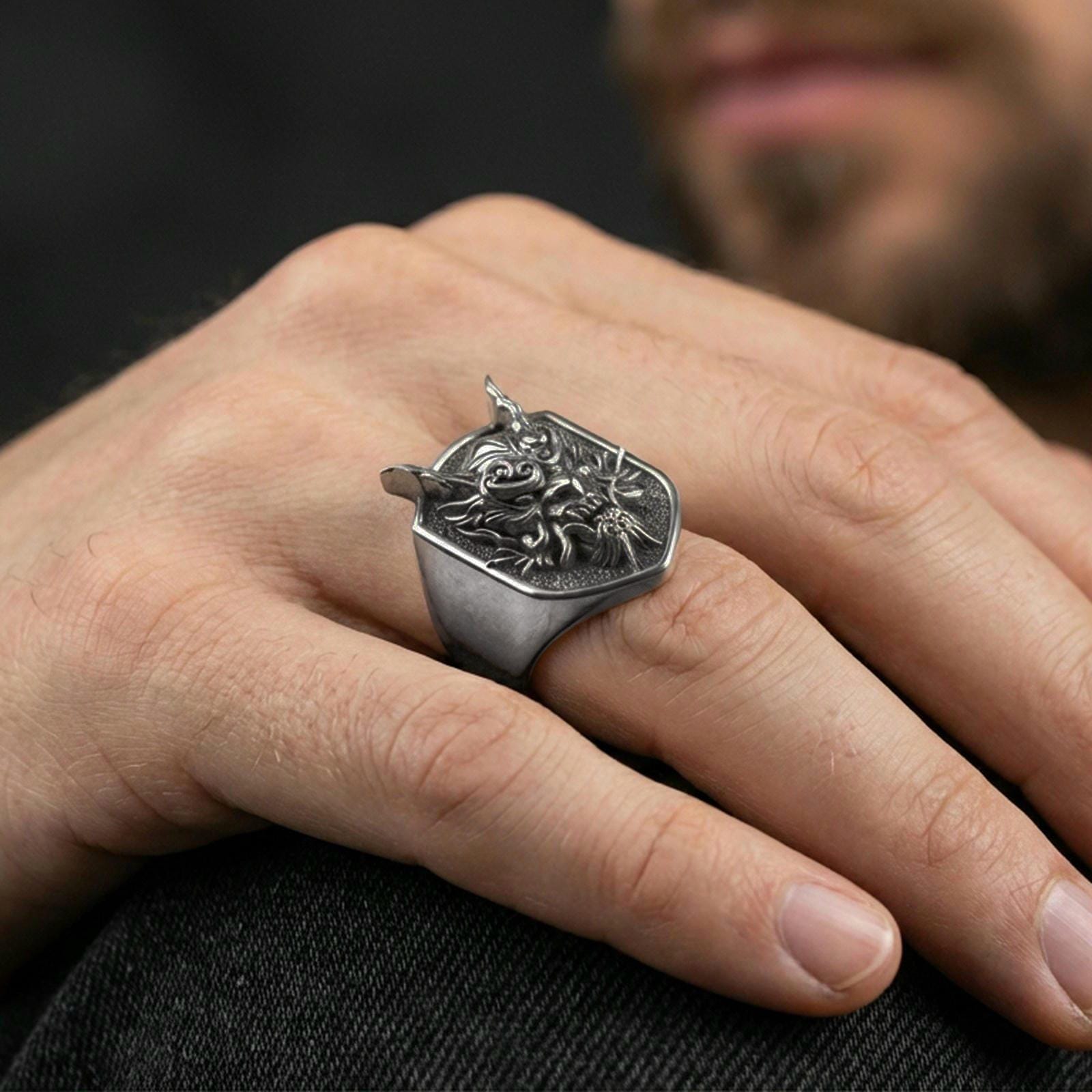 Oxidized horned oni mask ring worn on a finger, close-up lifestyle shot highlighting the deep carved demon face relief