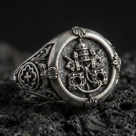 Oxidized sterling silver Saint Peter signet ring with Keys of Heaven and papal tiara relief, macro on black volcanic rock
