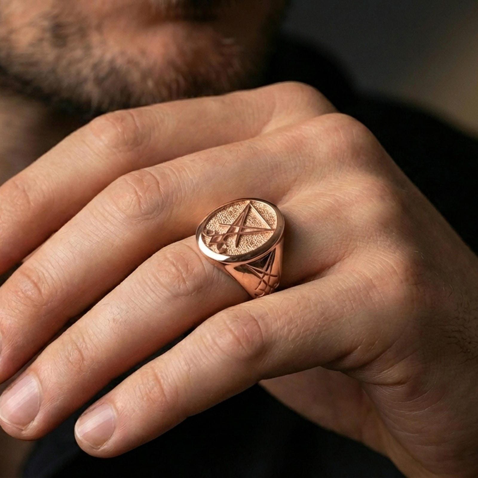 Rose gold plated Lucifer sigil ring worn on a finger, macro lifestyle shot showcasing the bold sigil relief and signet silhouette