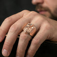 Load image into Gallery viewer, Rose gold plated finish knight signet ring on the finger, macro lifestyle shot showcasing the ornate shield border and raised warrior motif
