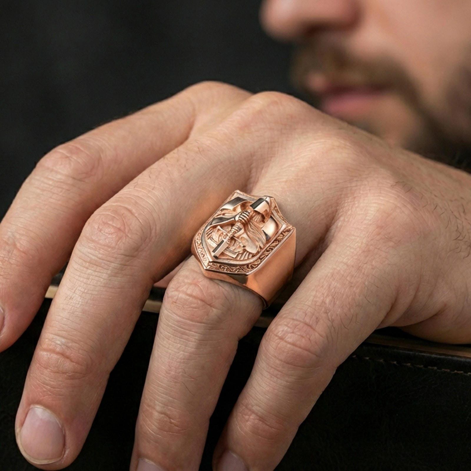 Rose gold plated finish knight signet ring on the finger, macro lifestyle shot showcasing the ornate shield border and raised warrior motif