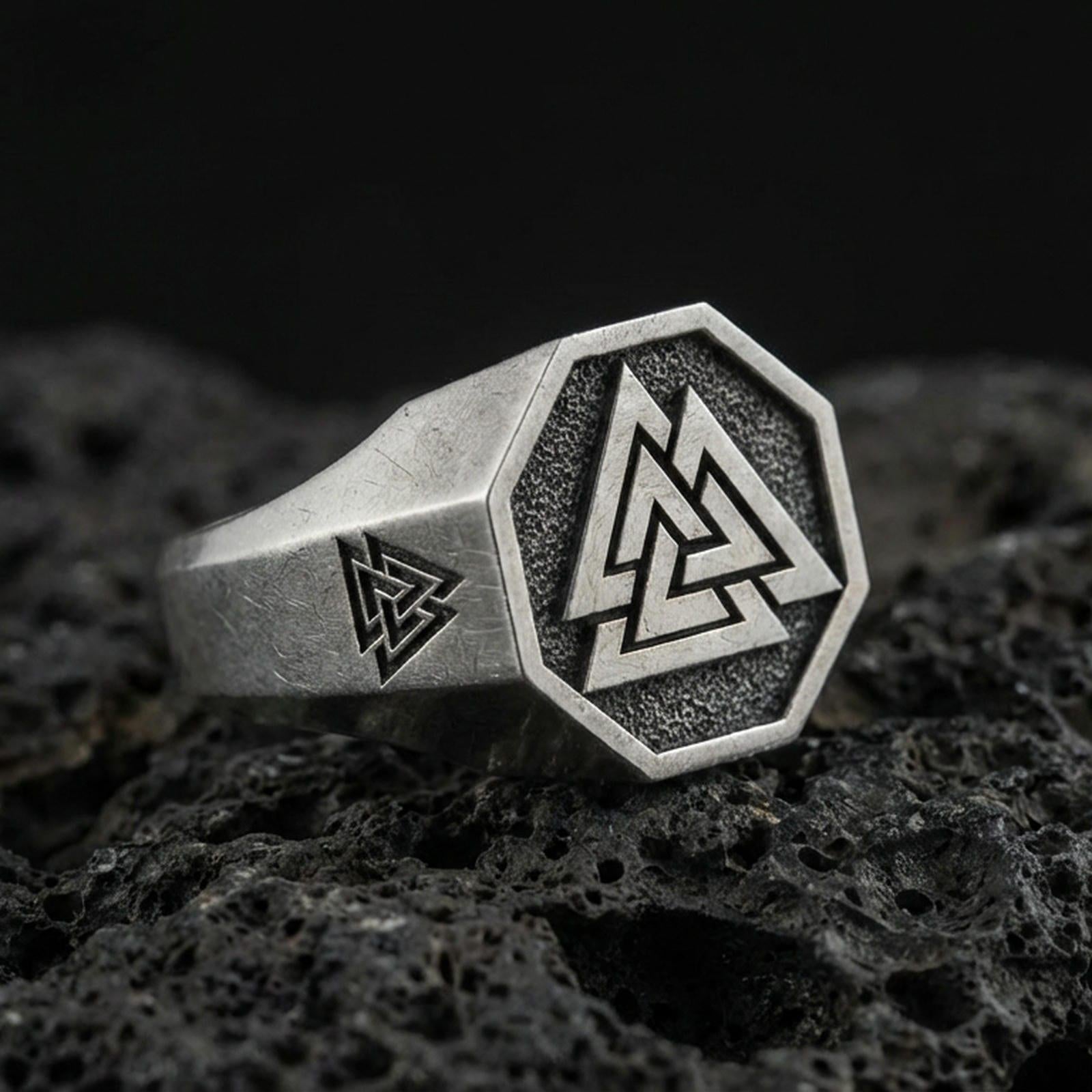 Sterling silver Valknut signet ring with an oxidized finish, octagon face featuring a Norse triple-triangle symbol, macro on black volcanic rock