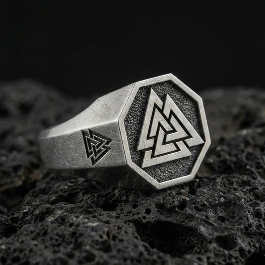 Sterling silver Valknut signet ring with an oxidized finish, octagon face featuring a Norse triple-triangle symbol, macro on black volcanic rock
