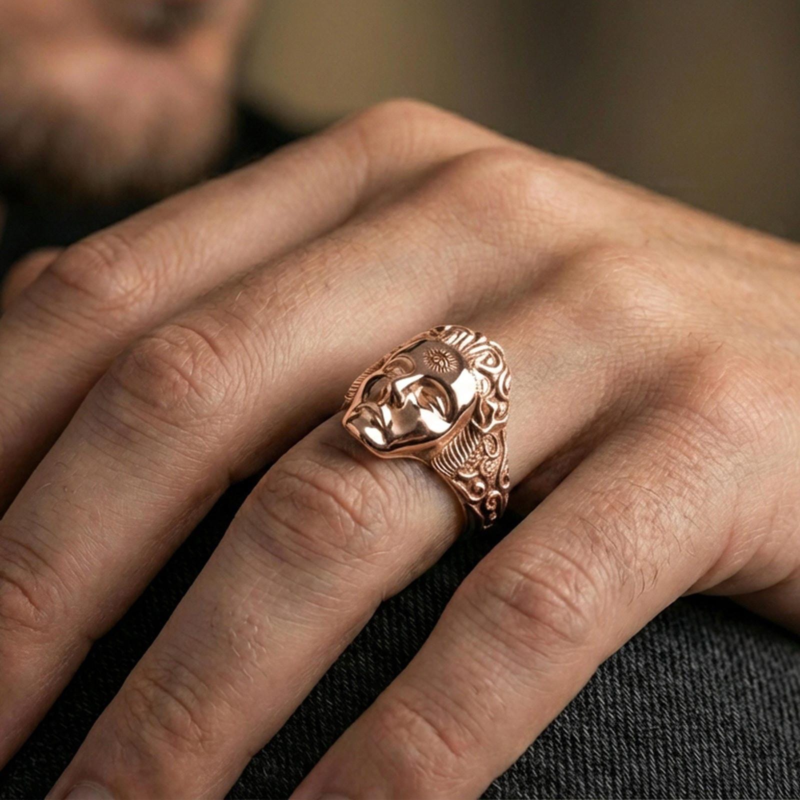Rose gold plated finish third eye face ring on the finger, macro lifestyle shot showcasing the serene face design and detailed side scrollwork