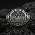 Load image into Gallery viewer, Sterling silver US eagle seal signet ring with an oxidized finish, detailed crest engraving and ornate shoulder accents, macro on black volcanic rock
