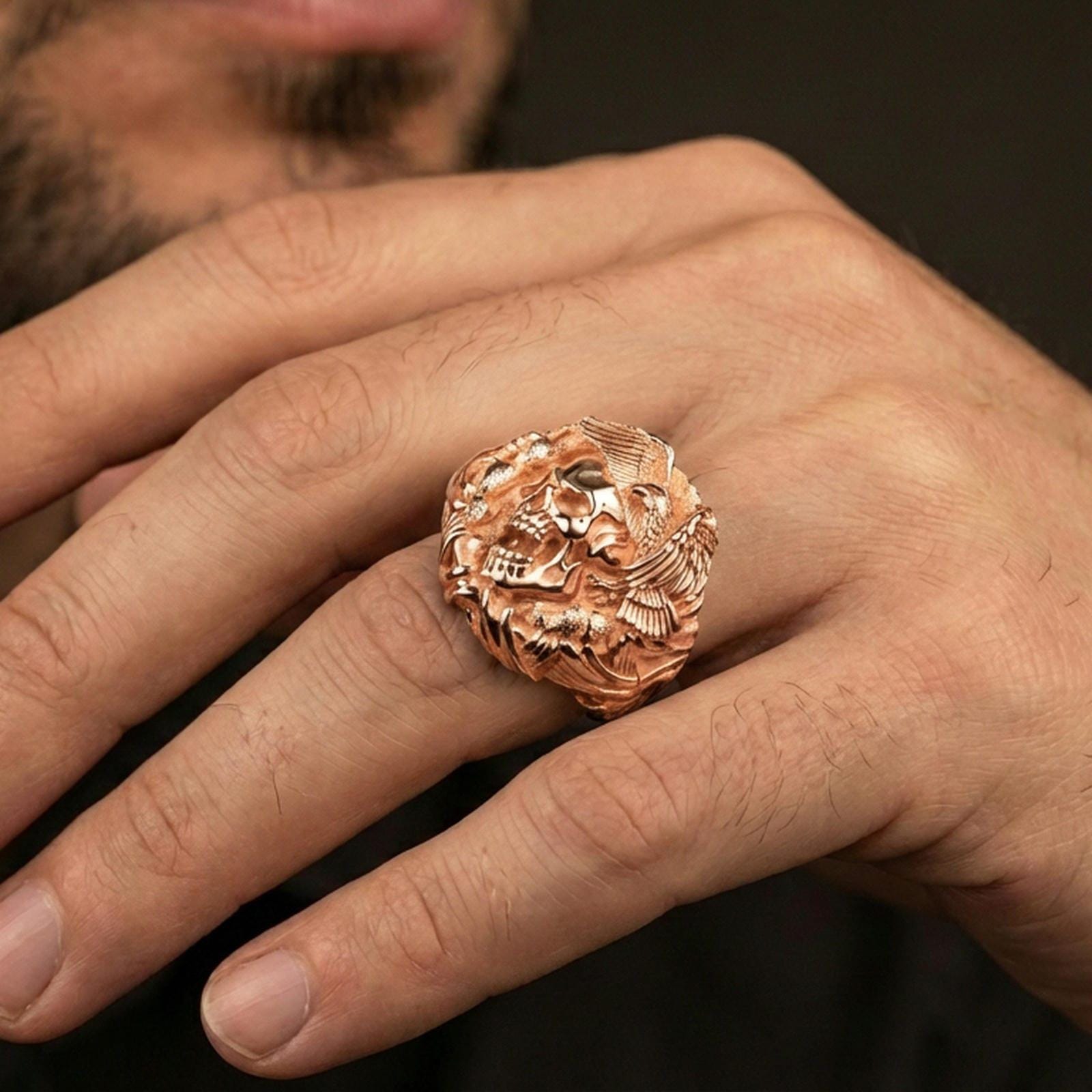 Rose gold plated finish skull and eagle ring on the finger, macro lifestyle shot showcasing the sculpted wings, talon details, and heavy signet look