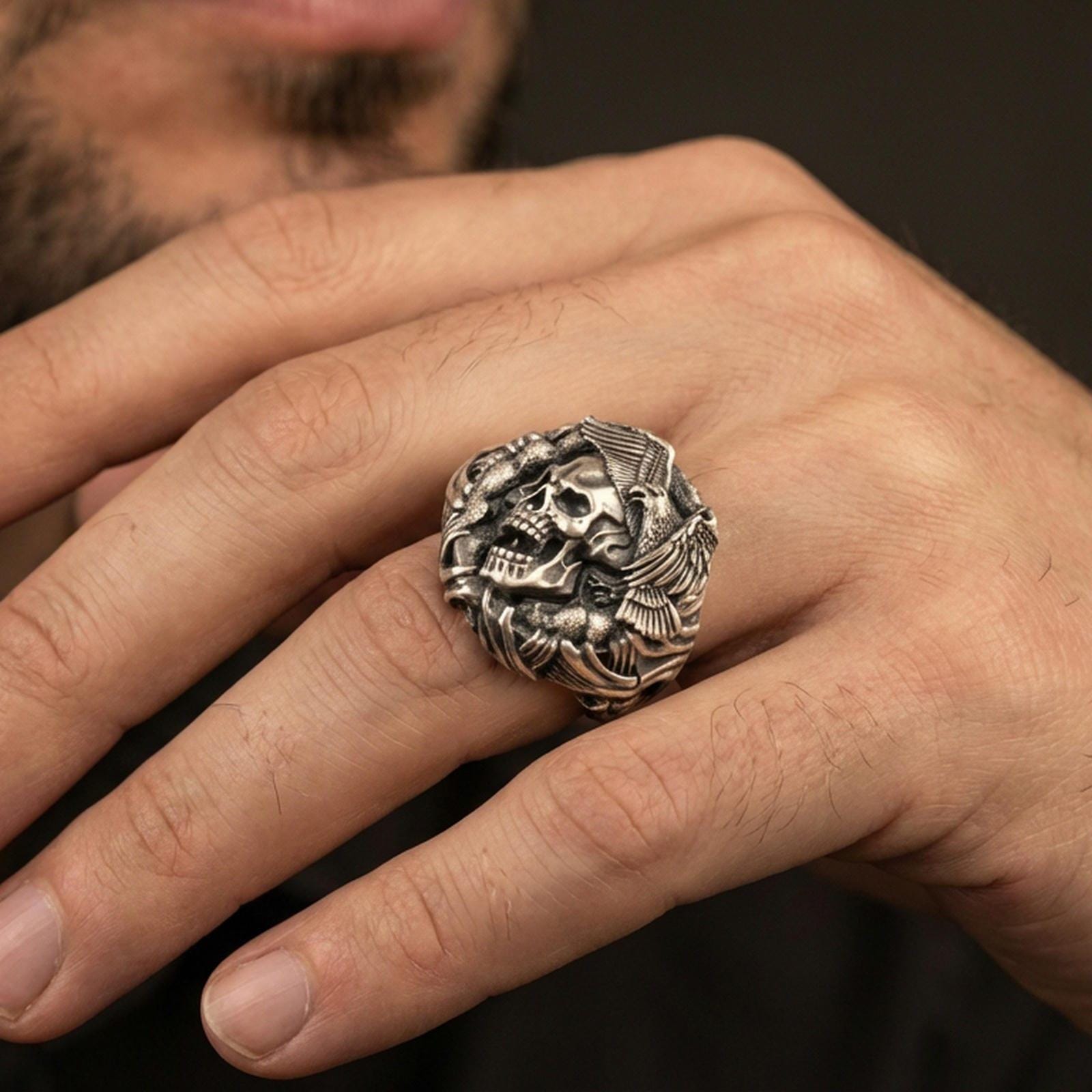 Oxidized finish skull and eagle ring worn on a finger, close-up lifestyle shot highlighting the winged skull relief and chunky statement profile
