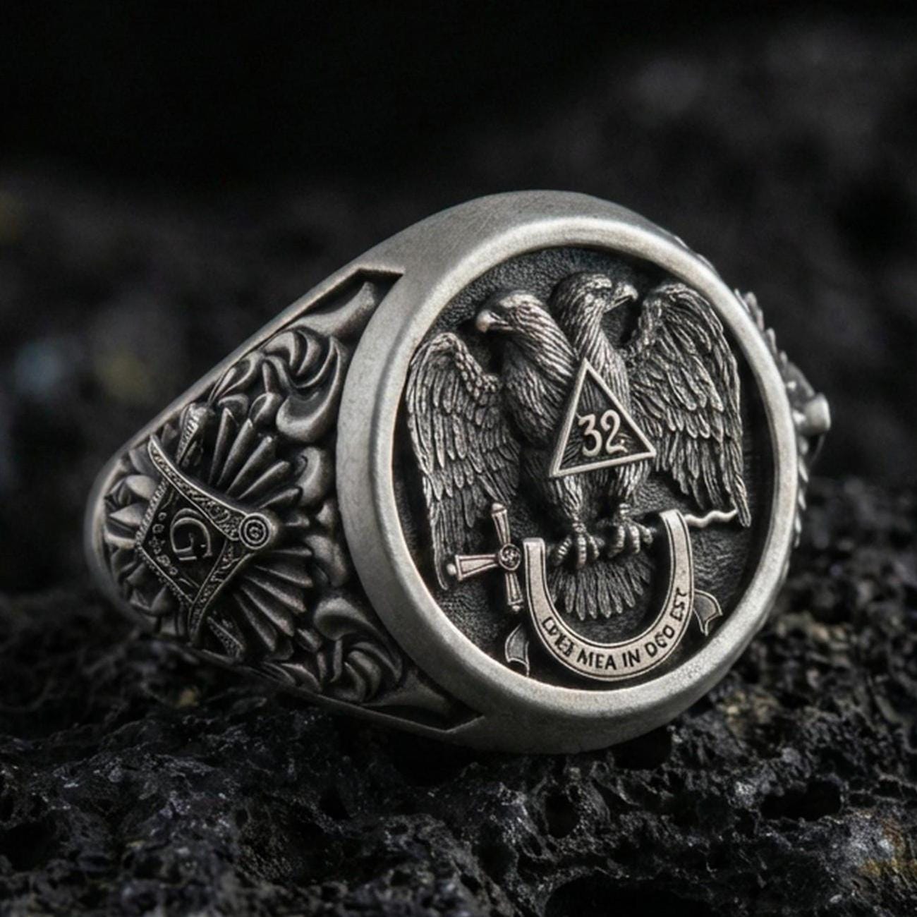 Sterling silver Masonic ring with an oxidized finish, double-headed eagle emblem and “32” triangle detail, macro on black volcanic rock