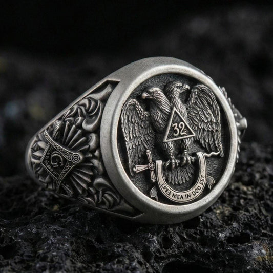 Sterling silver Masonic ring with an oxidized finish, double-headed eagle emblem and “32” triangle detail, macro on black volcanic rock