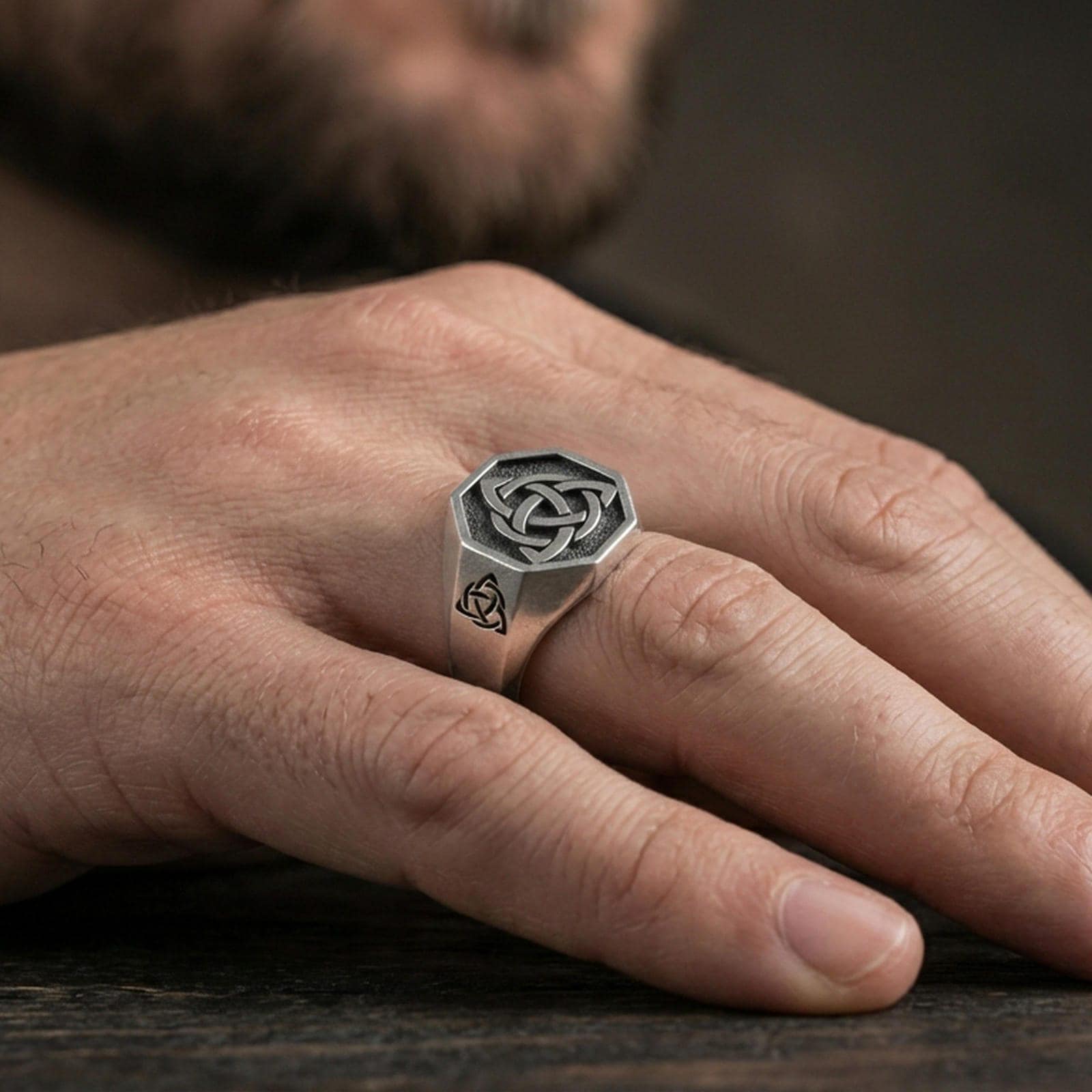 Oxidized finish sterling silver triquetra signet ring worn on a finger, close-up lifestyle shot highlighting the octagonal face and Celtic knot relief