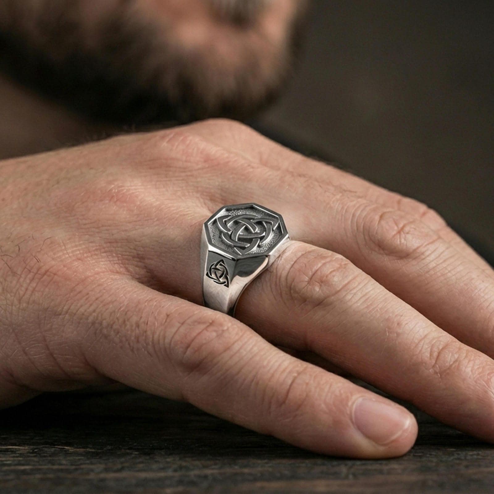 Polished silver finish triquetra Celtic knot signet ring on the finger, macro lifestyle image showing sharp edges and clean knotwork detail