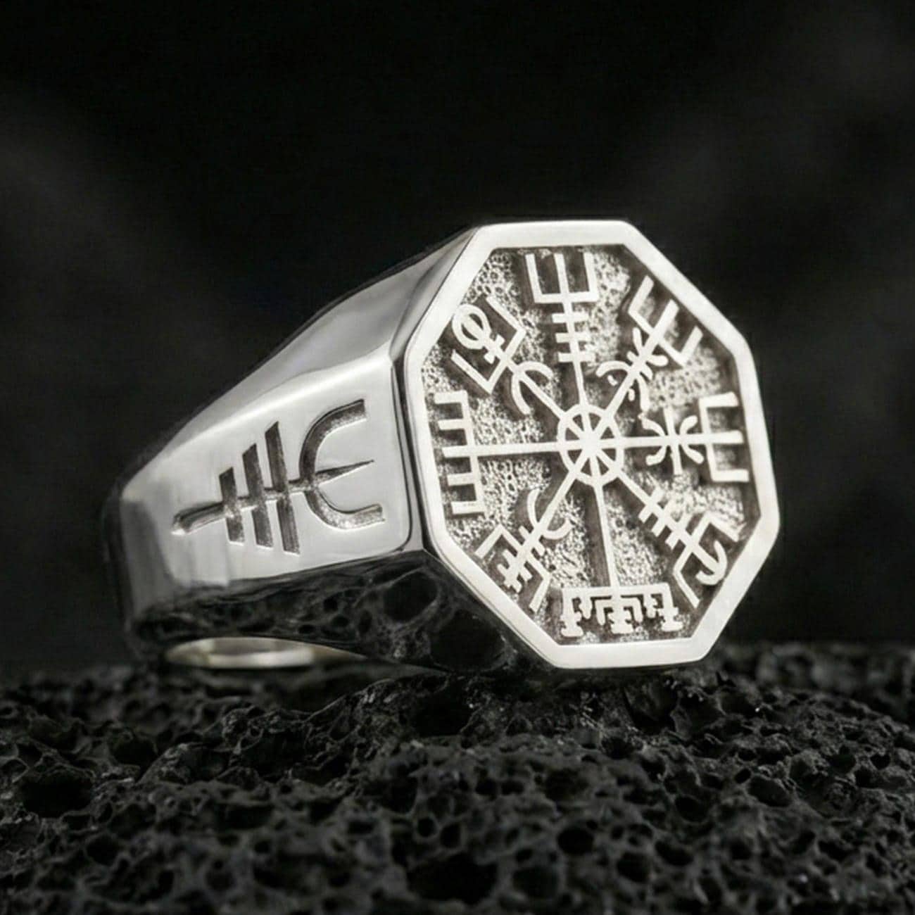Sterling silver Vegvisir signet ring in a polished silver finish, Norse runic compass symbol on an octagon signet, close-up on volcanic stone