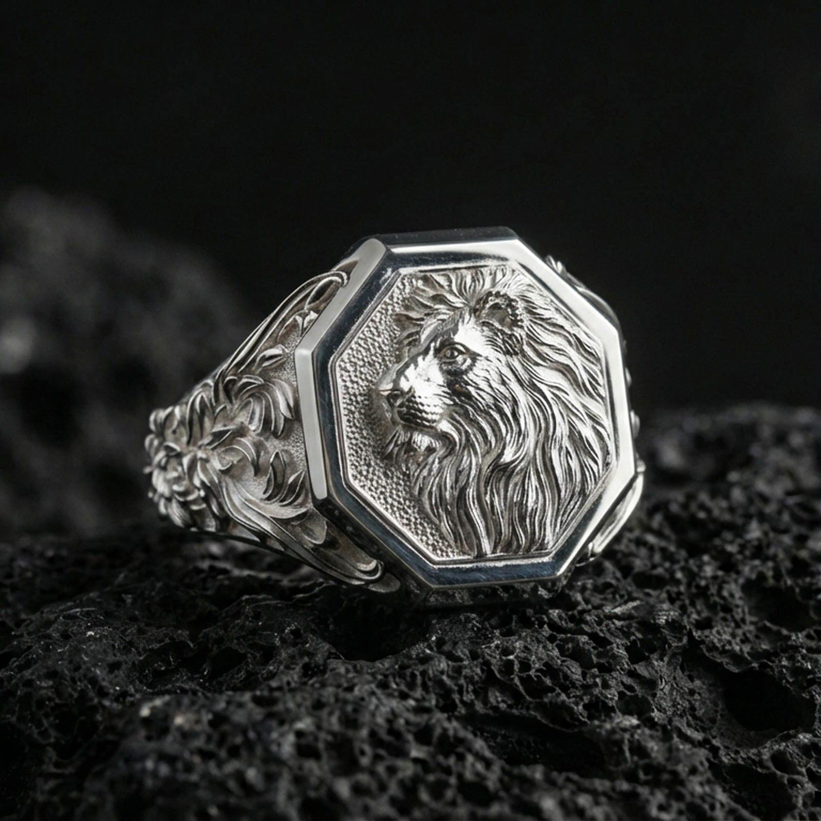 Polished silver lion signet ring on volcanic rock, octagonal signet face with detailed lion mane engraving and crisp beveled frame, premium close-up