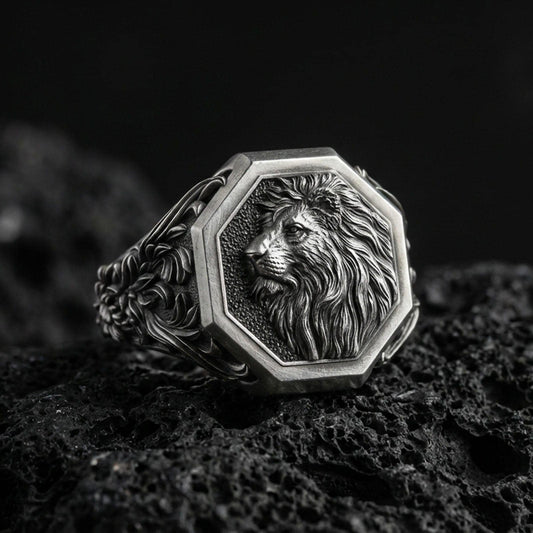 Oxidized sterling silver lion signet ring on volcanic rock, octagon face with raised lion head relief and deep textured background, macro studio photo