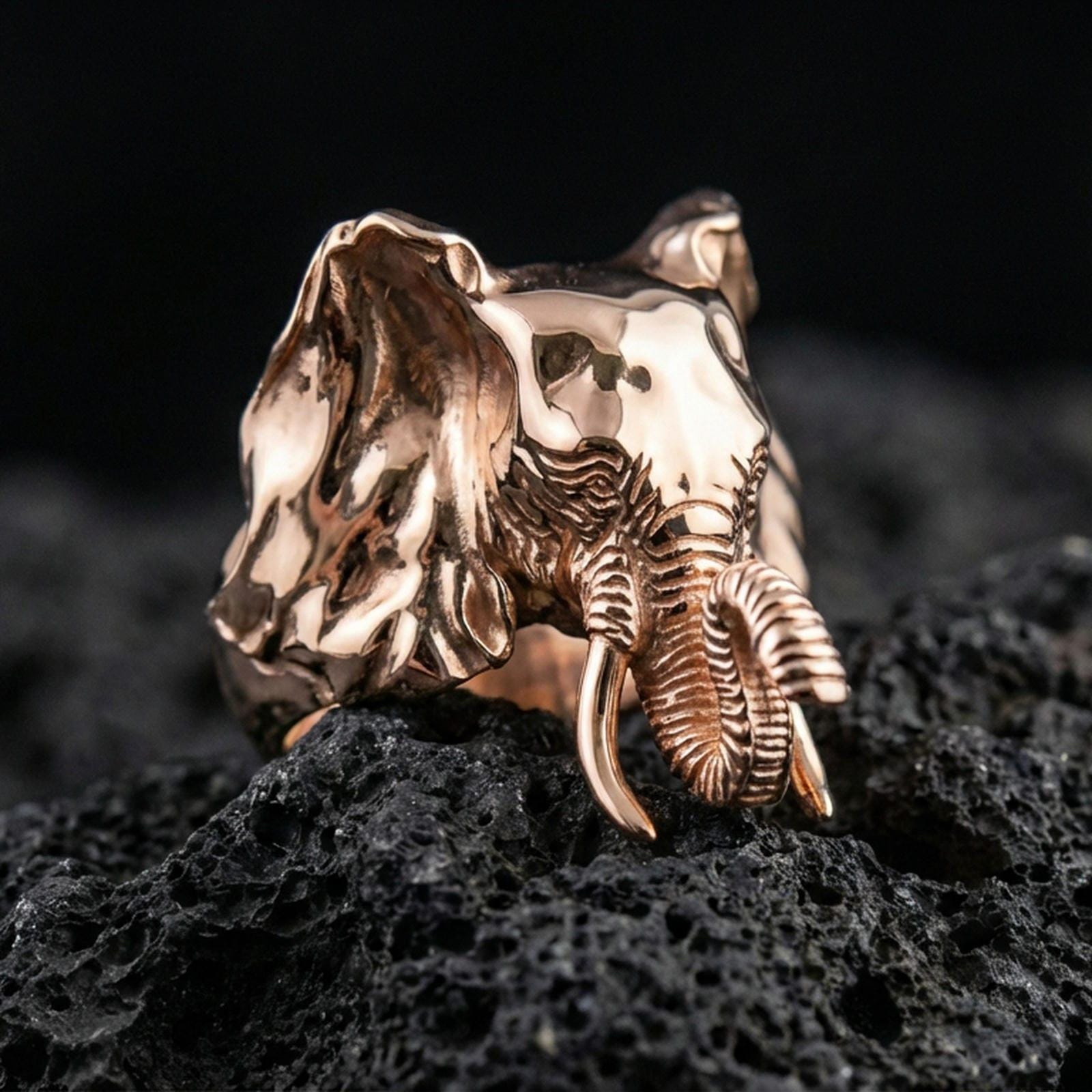 Rose gold plated elephant ring on volcanic rock surface, crisp close-up showcasing engraved lines and bold animal design