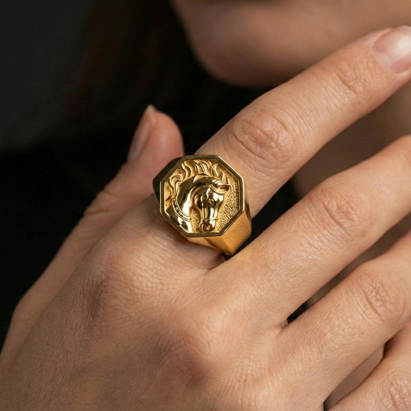 Gold plated horse signet ring worn on finger, lifestyle wear shot focusing on the detailed horse head relief