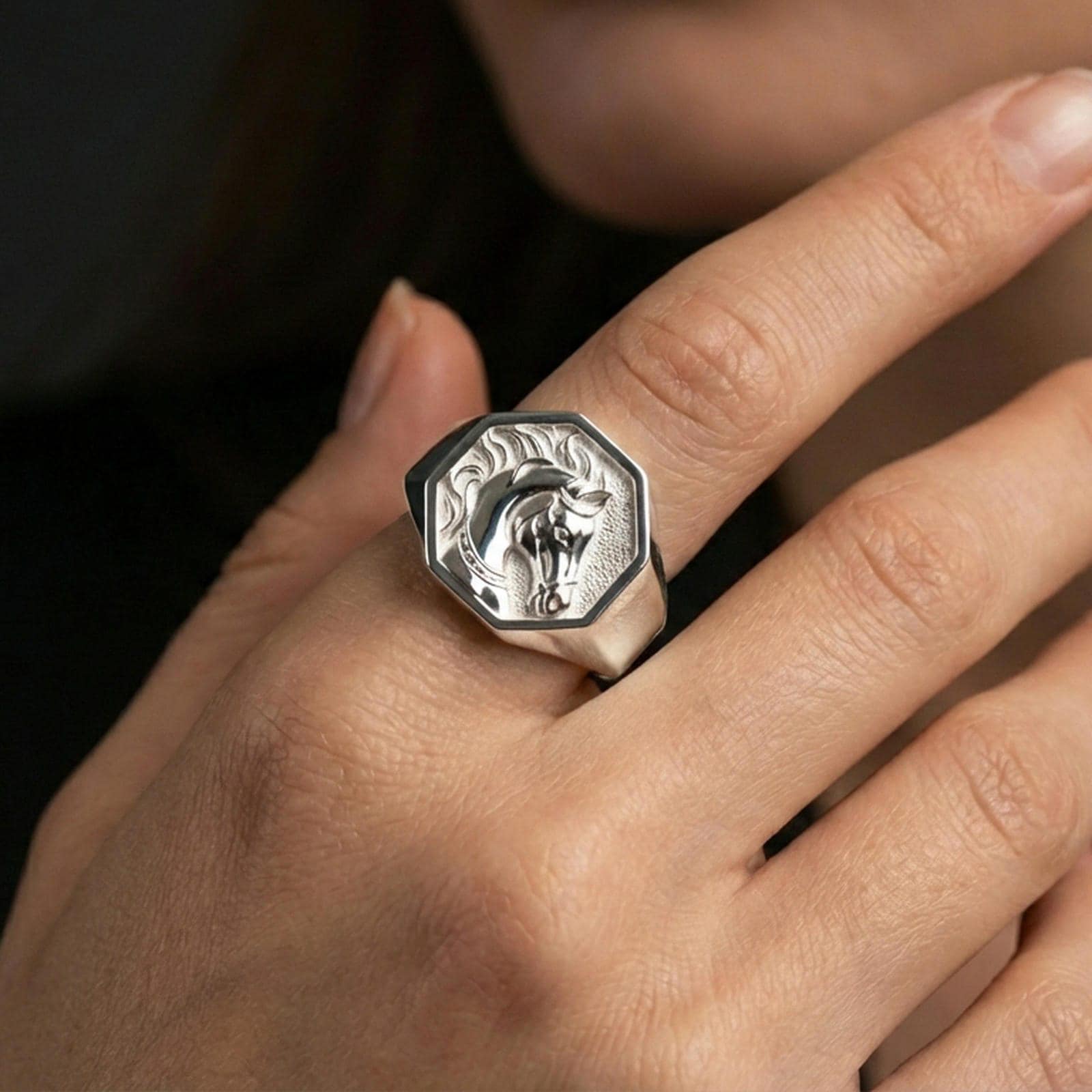 Polished silver horse ring on finger, natural hand pose highlighting the equestrian portrait and sharp bezel edges