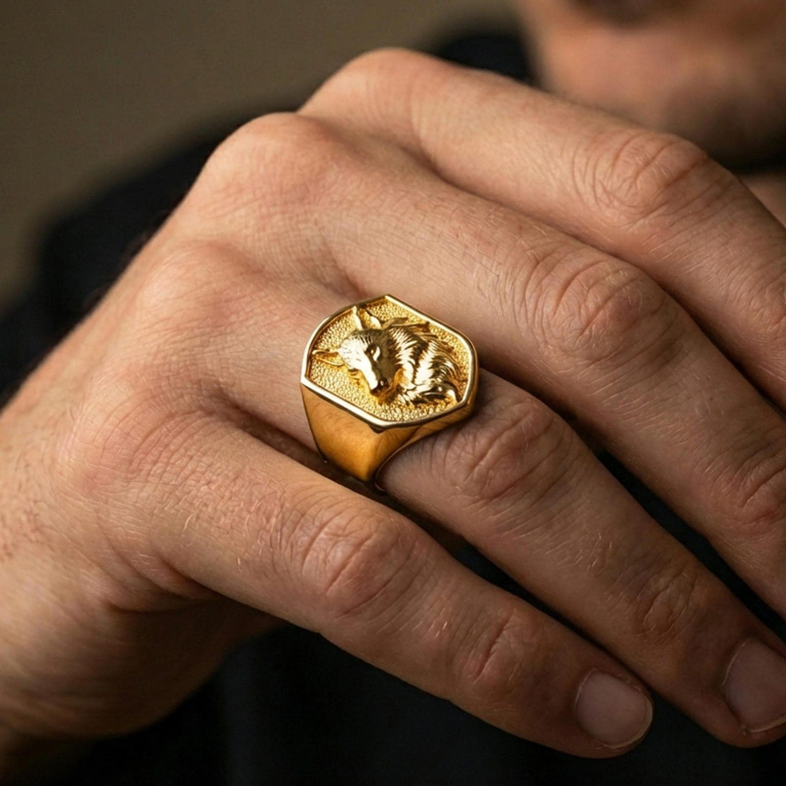Gold plated wolf signet ring worn on finger, lifestyle wear shot emphasizing the bold animal portrait and textured background