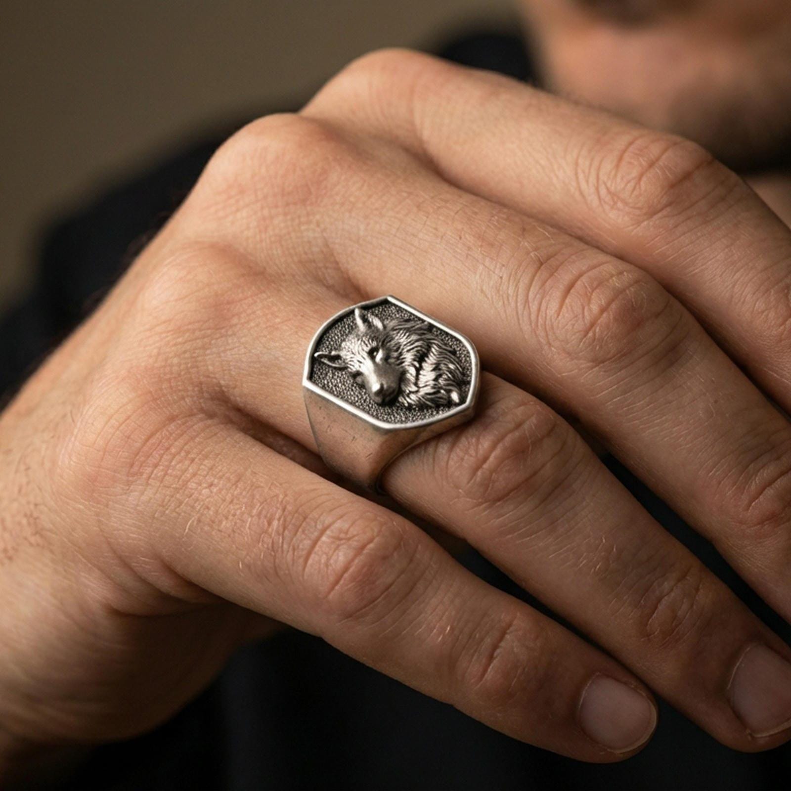 Oxidized wolf signet ring worn on finger, lifestyle close-up focusing on the shield face and carved wolf head profile