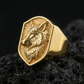 Load image into Gallery viewer, Gold plated wolf signet ring on porous volcanic stone, premium dark background emphasizing the engraved mane texture and bold profile
