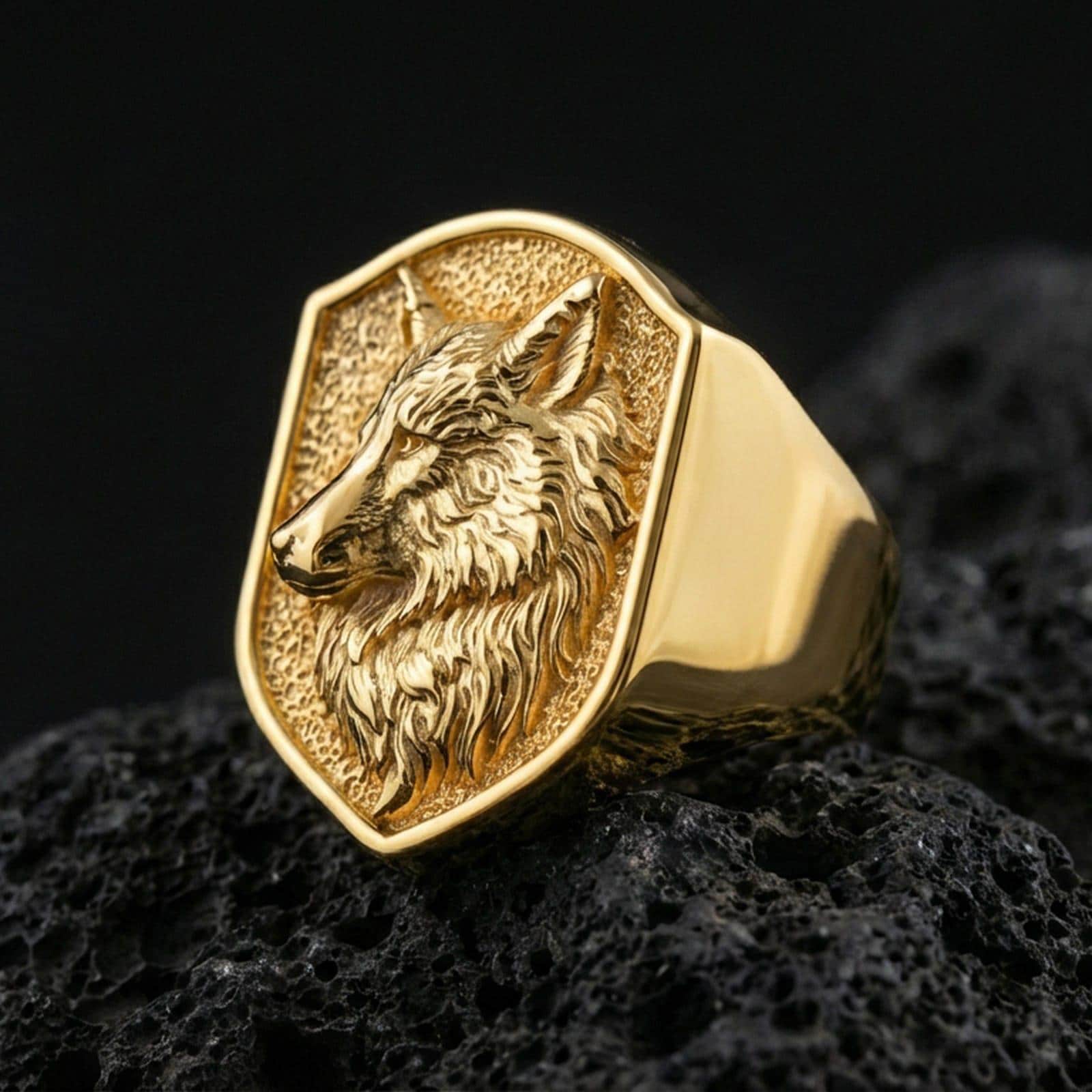 Gold plated wolf signet ring on porous volcanic stone, premium dark background emphasizing the engraved mane texture and bold profile