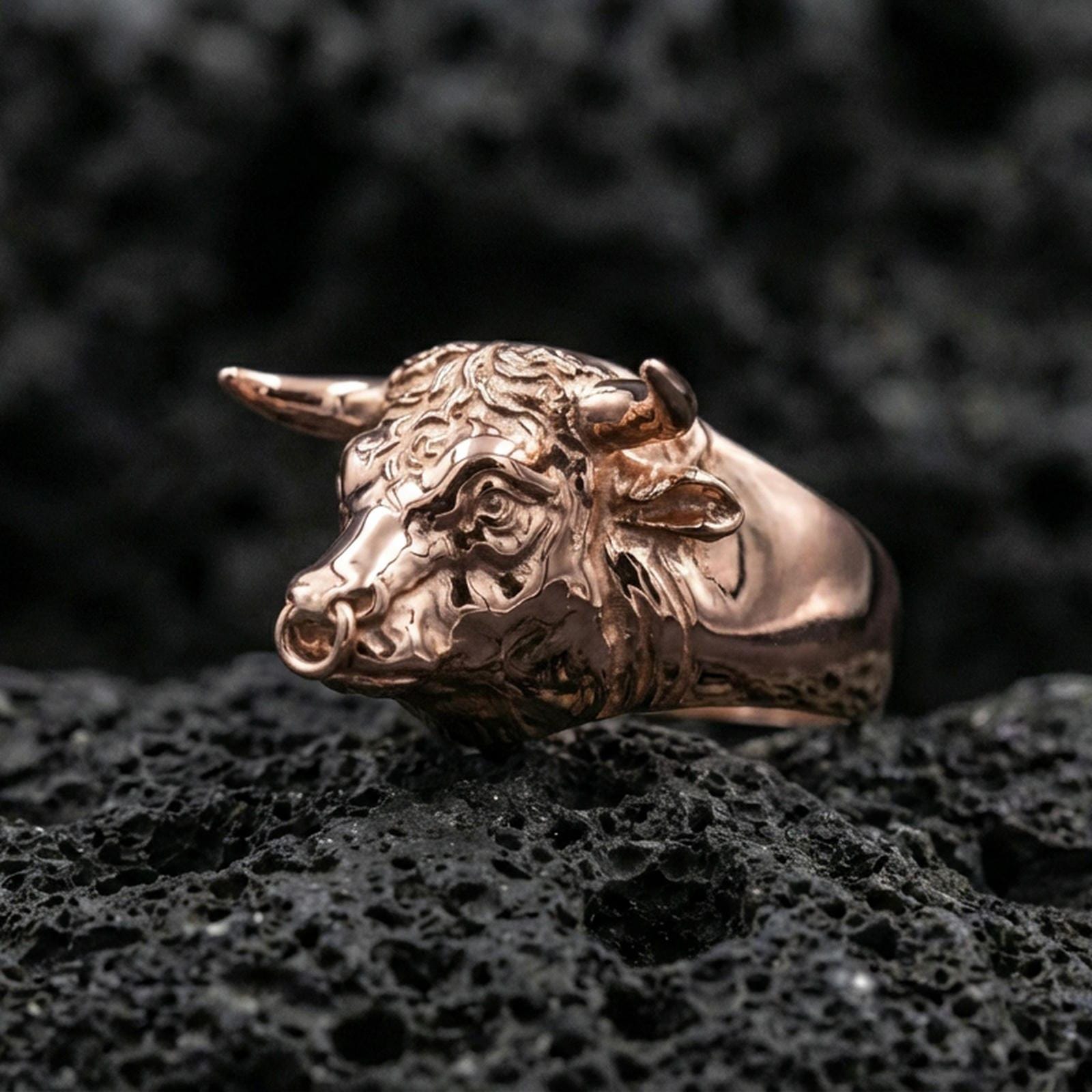 Rose gold plated bull ring on volcanic rock, sharp macro product photo showcasing the sculpted head, horns, and nose ring detail