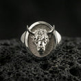 Load image into Gallery viewer, Polished silver bull head signet ring on volcanic rock surface, close-up highlighting the oval bezel and sculpted facial details
