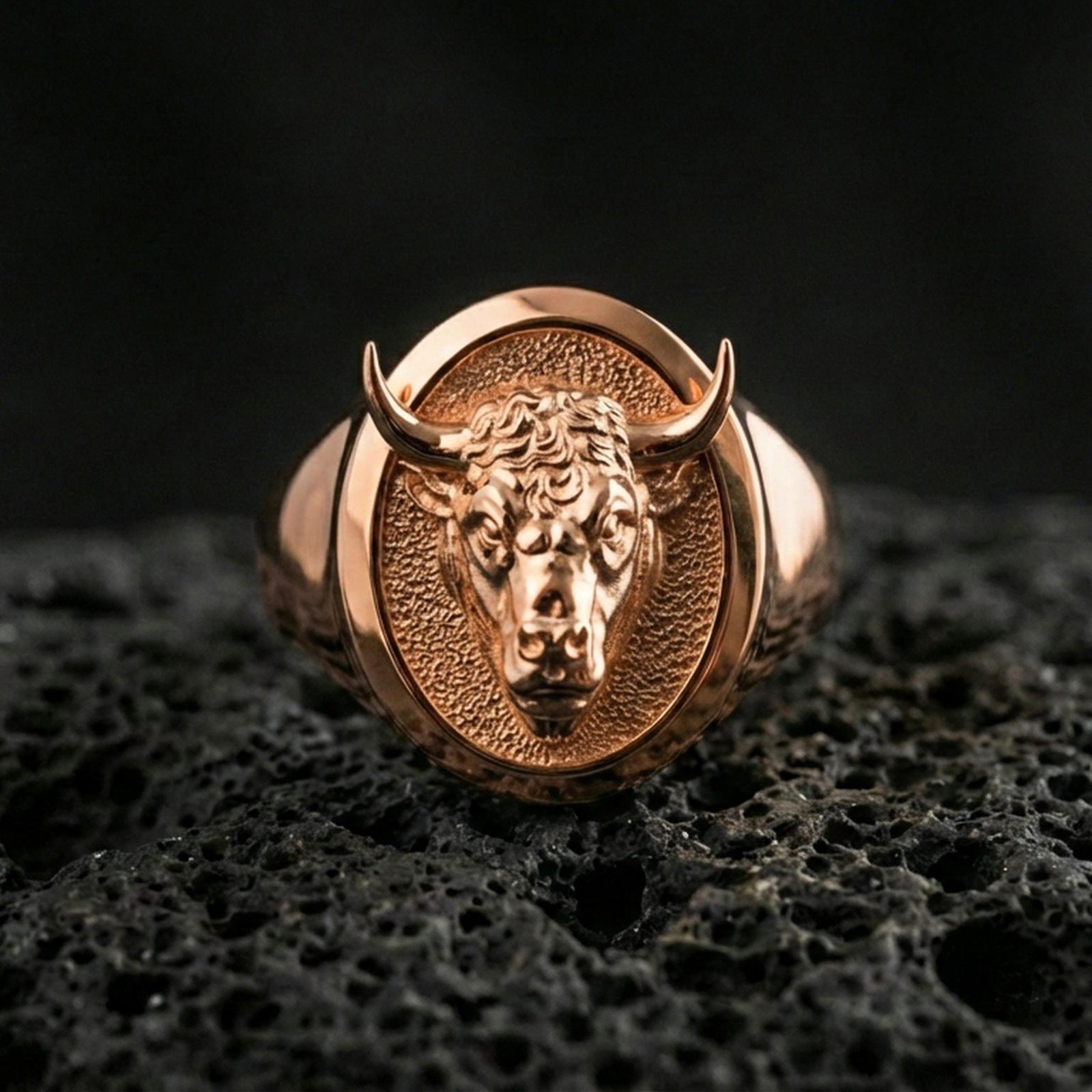 Rose gold plated bull head signet ring on volcanic rock, sharp macro product photo showcasing the oval top and detailed relief