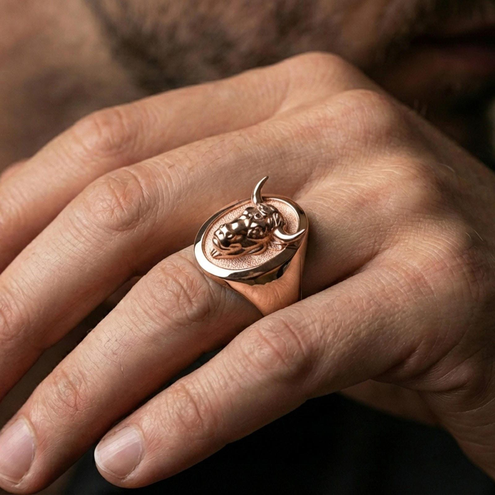 Rose gold plated bull ring on finger, close-up lifestyle photo showcasing the oval top and detailed bull head relief
