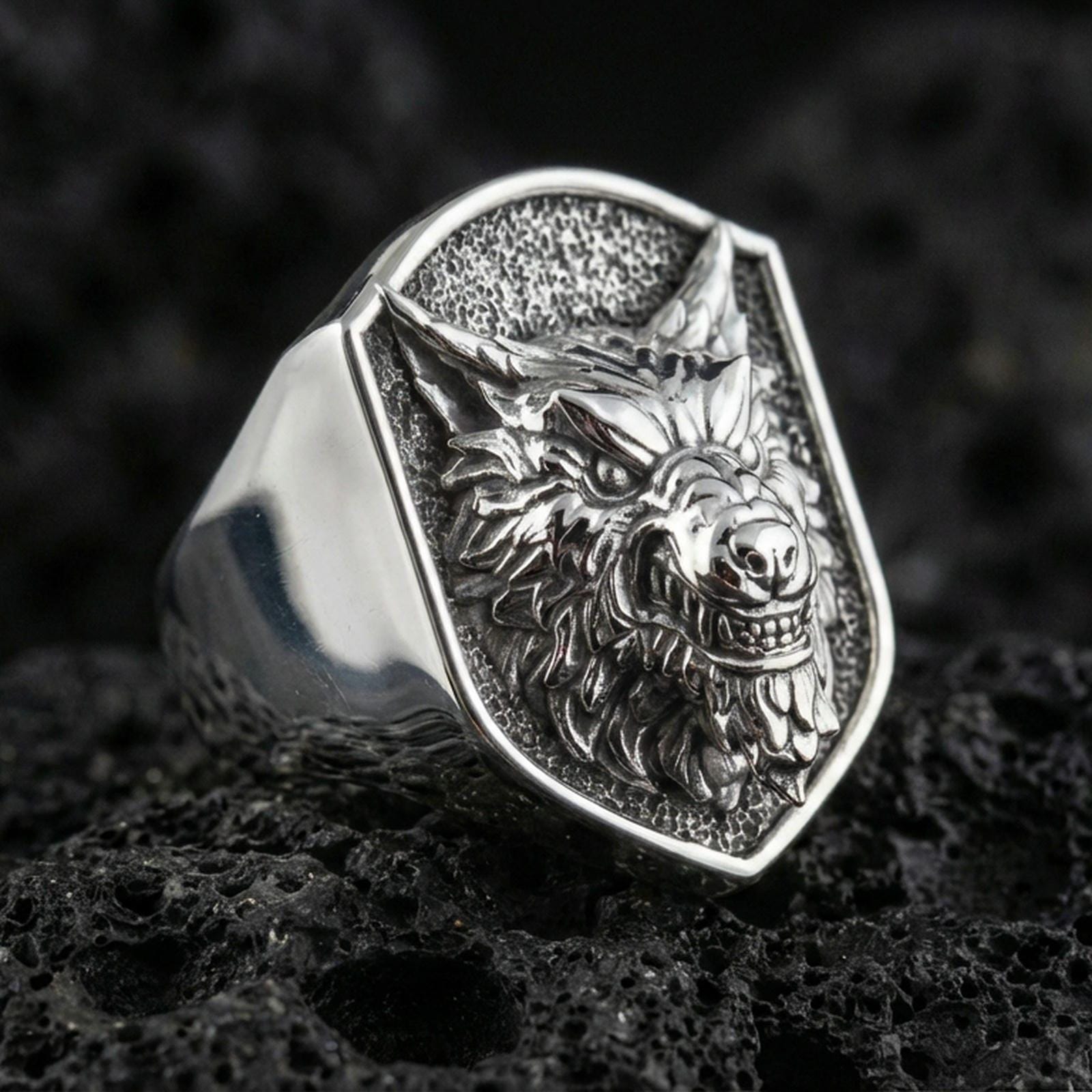 Polished silver wolf head ring on volcanic stone, sharp snarl design with premium studio lighting