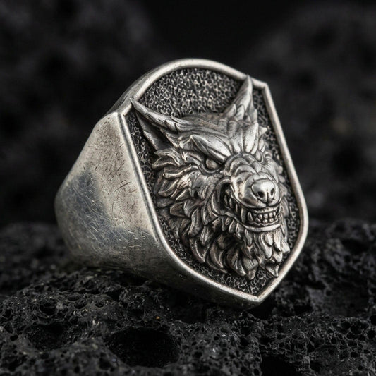 Oxidized sterling silver angry wolf head signet ring on volcanic rock, high detail macro closeup