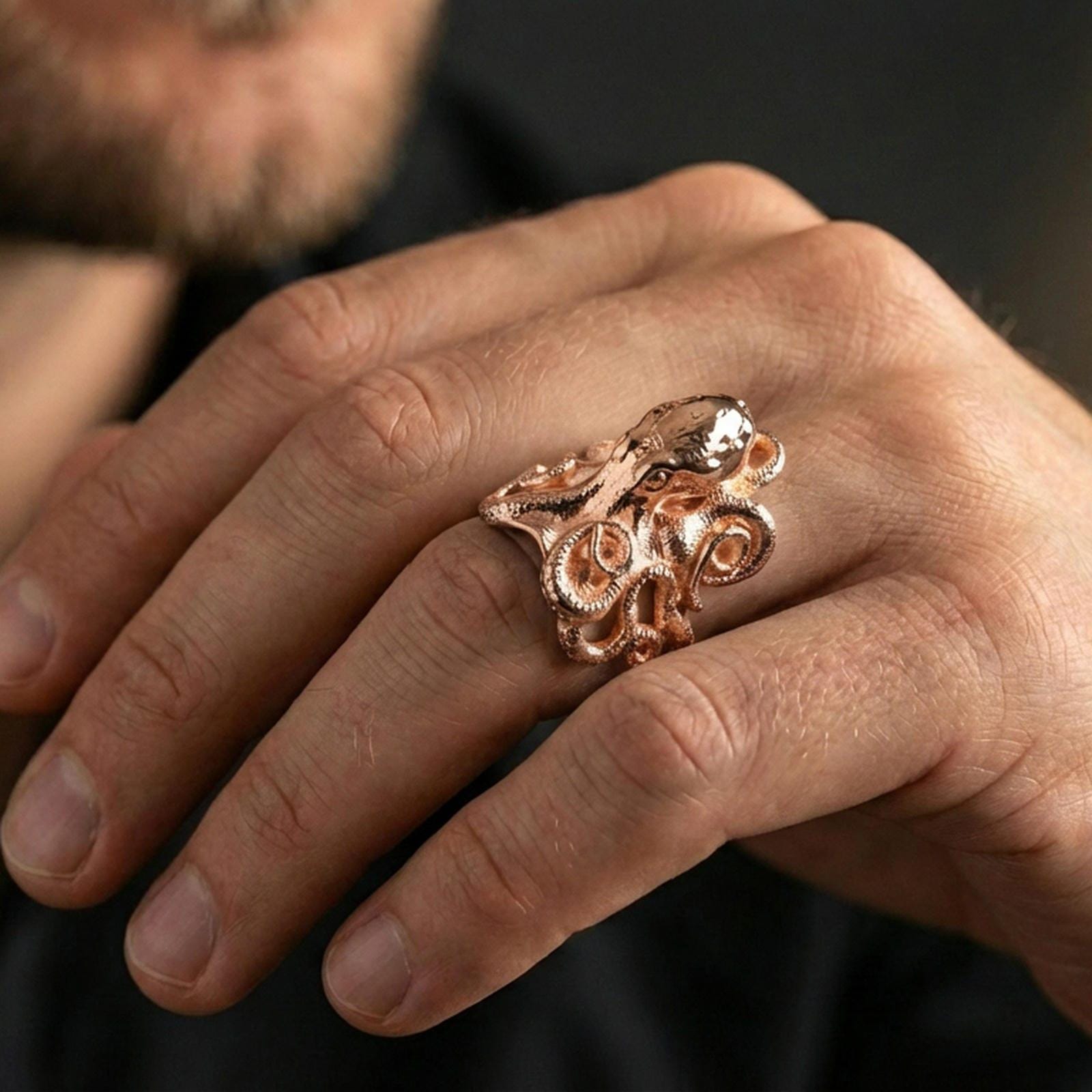 Rose gold plated octopus ring on finger, close-up lifestyle photo showcasing the octopus head, curled tentacles, and premium finish look