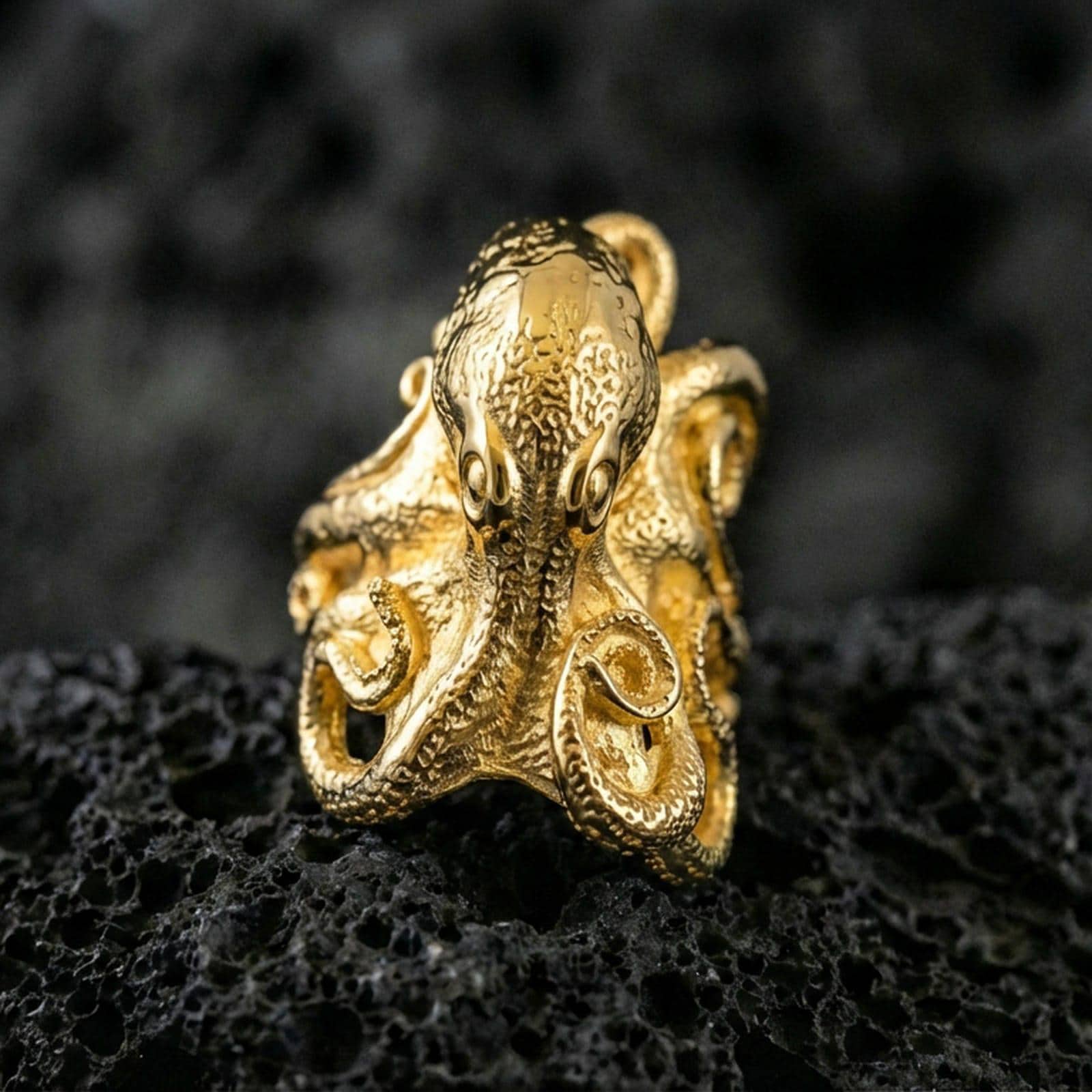 Gold plated octopus ring on porous volcanic stone, premium dark studio shot emphasizing detailed tentacle suction cups and bold nautical design