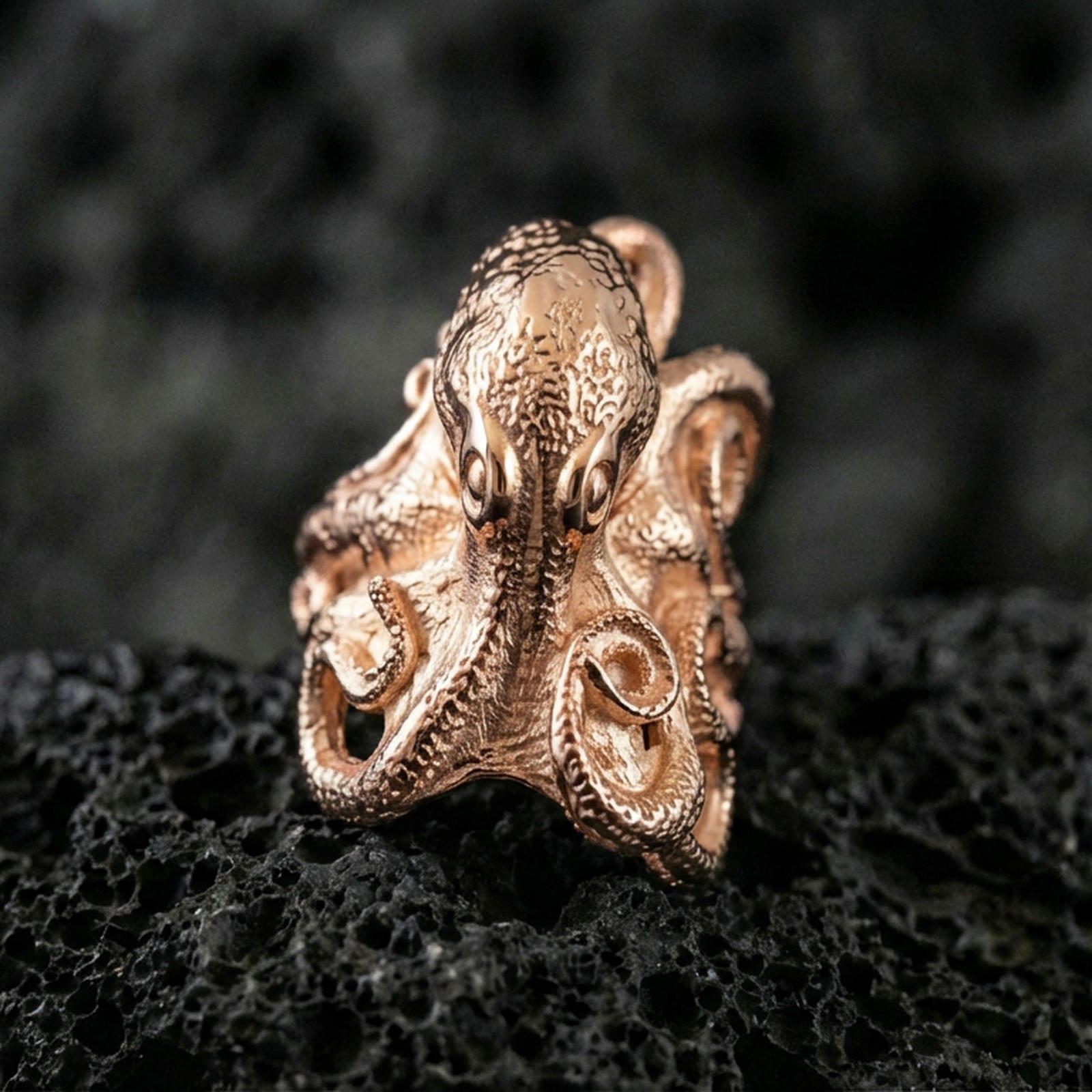 Rose gold plated octopus ring on volcanic rock, sharp macro product photo showcasing the octopus head and curled tentacles in high detail