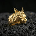 Load image into Gallery viewer, Gold plated lynx ring on porous volcanic stone, premium dark studio shot emphasizing the wild cat head relief and engraved fur texture
